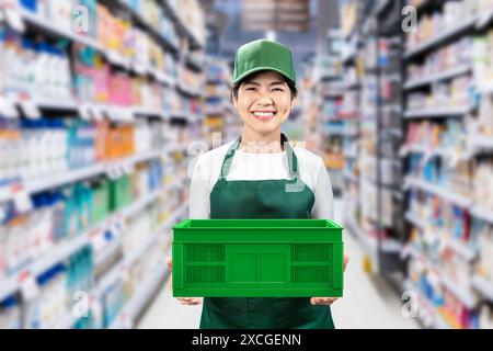 I venditori asiatici indossano un grembiule verde e un berretto verde sorridenti nel negozio al dettaglio Foto Stock