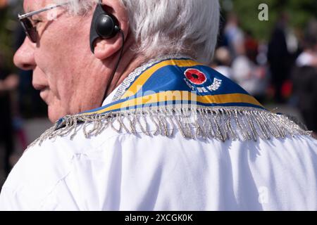 Membro dell'ordine arancione che indossa una collaretta blu con papavero e la scritta "Lever We Forget" sul colletto. Royal Landing Parade, Carrickfergus 8 giugno 2024. Foto Stock