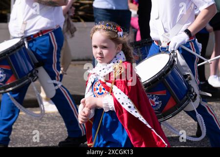 Giovane ragazza in abito elegante con Rathcoole Sons of Kai alla parata annuale Royal Landing a Carrickfergus, Irlanda del Nord, 8 giugno 2024. Foto Stock