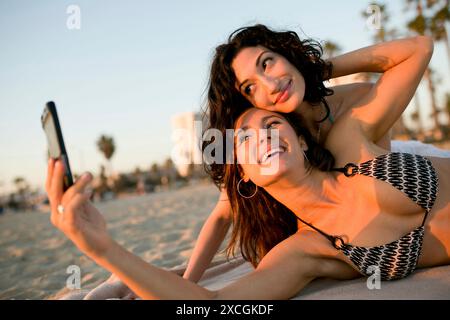 Due donne si fanno una foto alla spiaggia. Foto Stock