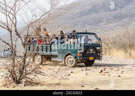 Un grande veicolo safari in cantera da 20 posti pieno di avvistatori di fauna selvatica nel arido e polveroso Parco Nazionale di Ranthambore, Rajasthan, India settentrionale Foto Stock