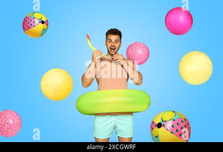 Uomo felice con anello gonfiabile tra palle da spiaggia cadenti su sfondo azzurro. Atmosfera estiva Foto Stock