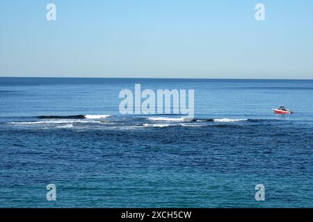 Pesca ricreativa in un bellissimo mare azzurro sotto un cielo azzurro vicino a una barriera rocciosa semi sommersa al largo del promontorio di Cronulla Foto Stock