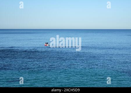 Pesca ricreativa in un bellissimo mare azzurro sotto un cielo azzurro vicino a una barriera rocciosa semi sommersa al largo del promontorio di Cronulla Foto Stock