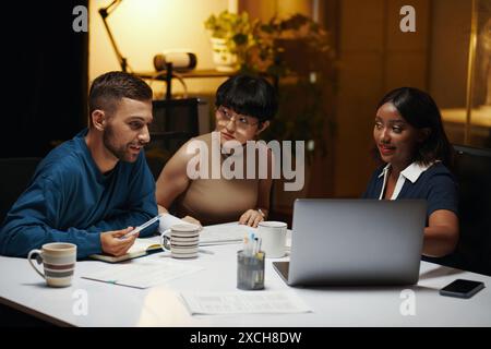 Uomo d'affari che condivide idee con i colleghi durante una riunione notturna Foto Stock