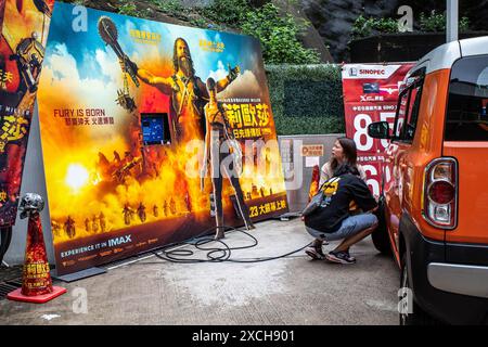 Hong Kong, Cina. 9 giugno 2024. Due clienti aggiungono aria agli pneumatici accanto a un poster di un film in una stazione di servizio a Quarry Bay come parte di un legame promozionale tra SINOPEC e Warner Bros Per Furiosa: A Mad Max Saga, basato su una storia post-apocalittica in cui la benzina è una risorsa finita e i tiranni combattono nelle Terre desolate utilizzando veicoli moddati, il tie-in è una strategia di marketing unica per entrambe le parti. (Credit Image: © Ben Marans/SOPA Images via ZUMA Press Wire) SOLO PER USO EDITORIALE! Non per USO commerciale! Foto Stock