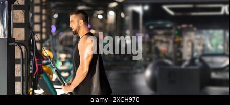 Uomo che si sta allenando sulla macchina via cavo nella moderna palestra Foto Stock