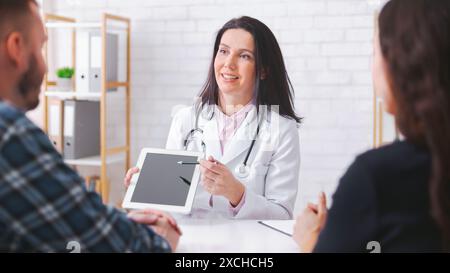 Lady Doctor spiega le informazioni mediche ai pazienti su tablet Foto Stock
