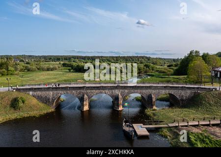 Ponte di pietra che attraversa il fiume con acqua corrente sotto. Kandava, Lettonia Foto Stock