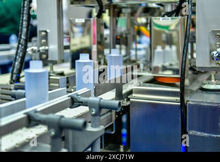 Bottiglie di plastica bianche in un nastro trasportatore su una macchina di riempimento verticale automatica di alta qualità. nella linea di produzione della fabbrica Foto Stock