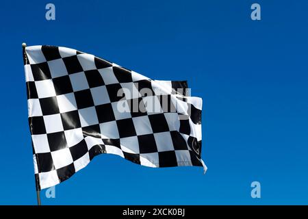 Una bandiera a scacchi contro il cielo blu all'aperto, vista dall'angolo basso Foto Stock