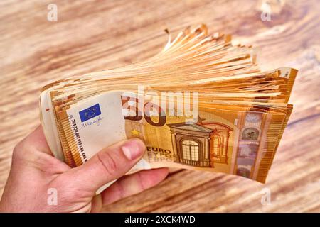 Germania - 17 giugno 2024: Mano di una persona che detiene un pacchetto di banconote, 50 banconote in euro. Concetto, ricchezza in vecchiaia attraverso la pensione e il denaro. *** Mano einer persona hält ein Bündel Geldscheine, 50 Euro Banknoten in der hand. Konzept, Reichtum im alter durch Rente und Bargeld. Foto Stock