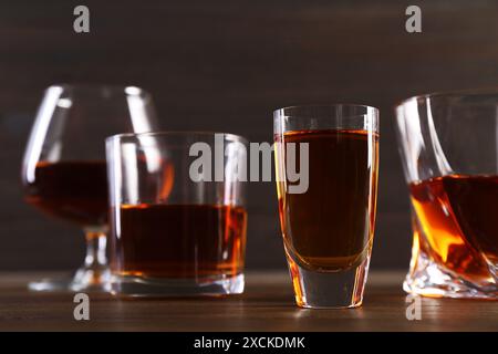 Diversi deliziosi liquori in bicchieri su un tavolo di legno Foto Stock