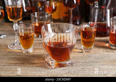 Diversi deliziosi liquori in bicchieri su un tavolo di legno Foto Stock