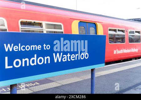 Cartello con la scritta "Welcome to London Waterloo" in lettera bianca sul binario dove i passeggeri salgono a bordo di un treno sud-occidentale. Inghilterra Regno Unito Foto Stock