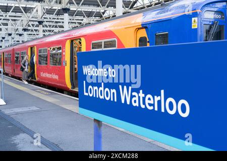 Cartello con la scritta "Welcome to London Waterloo" in lettera bianca sul binario dove i passeggeri salgono a bordo di un treno sud-occidentale. Inghilterra Regno Unito Foto Stock