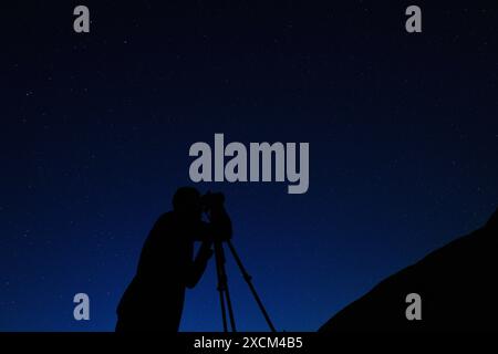 Fotografo che scatta foto del cielo notturno. Silhouette dell'uomo sullo sfondo del cielo stellato notturno. Stelle Foto Stock