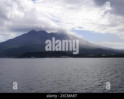 Isola vulcanica di Sakurajima con vulcano fumante a Kyushu, Giappone. Vista dal mare, vicino a Kagoshima. Vulcano fumante e cielo nuvoloso Foto Stock