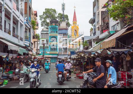 Ho chi Minh City, Vietnam - 9 giugno 2024: Una piccola strada di mercato con una chiesa cattolica sullo sfondo nel quartiere storico di Cholon. Foto Stock