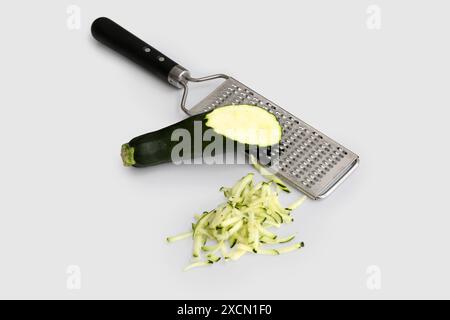 Zucchine verdi fresche e grattugia su fondo bianco Foto Stock