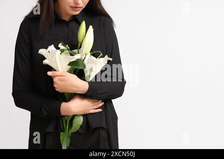 Giovane donna con bouquet funebre di fiori di giglio su sfondo bianco Foto Stock