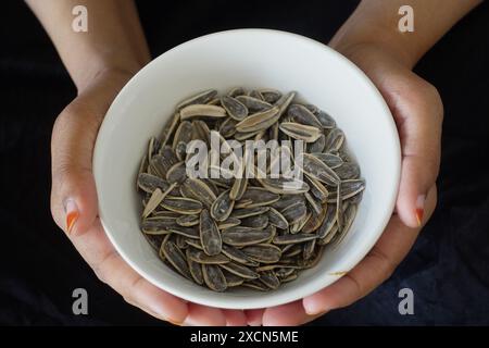 donna che tiene in mano una ciotola di semi di fiori di sole Foto Stock