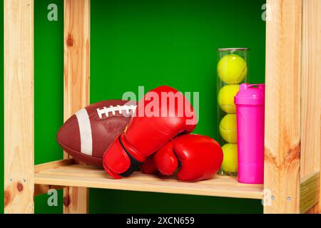 Ripiani con diverse attrezzature sportive contro il muro verde Foto Stock