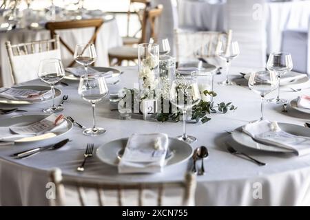 Un tavolo da nozze ricoperto da una tovaglia bianca, decorato con fiori, candele, bicchieri e posate. Foto Stock