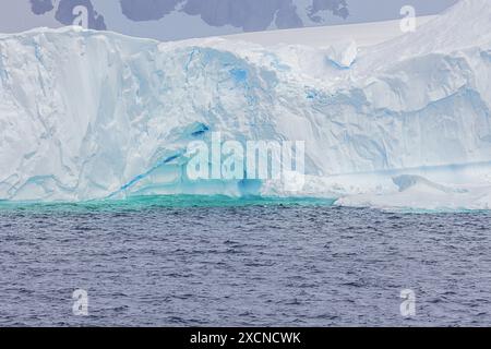 Colori intensi dal ghiaccio blu nel cuore di un iceberg tra Lemaire e Bryde Island Foto Stock