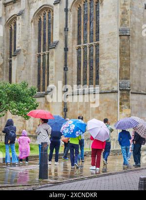 Turisti cinesi con ombrelloni fuori dalla cappella del Trinity College, Università di Cambridge, Inghilterra, in una giornata umida e piovosa. Foto Stock