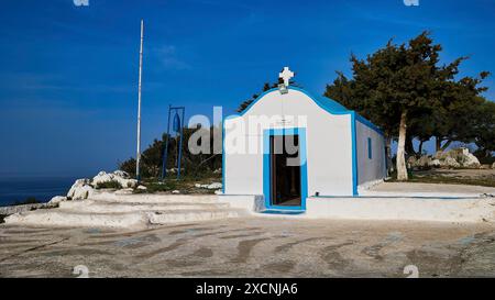 Profitis Ilias Chapel, cappella bianca con accenti blu su una collina circondata da alberi e cielo blu, Anthony Quinn Bay, Vagies Bay, Rodi, Dodecaneso Foto Stock