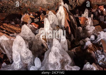 Stalagmiti di ghiaccio (ghiaccioli) si sono formati sulla superficie di roccia vulcanica di ferro rosso nel tunnel di lava (Raufarholshellir) in Islanda. Foto Stock