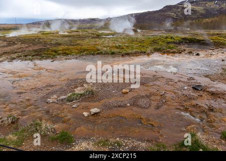 Area geotermale di Geysir nella valle Haukadular, Islanda, con sorgenti calde fumanti, corsi d'acqua calda e acqua solforosa marrone, nessuna gente. Foto Stock