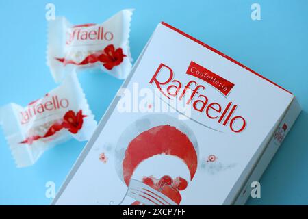 KIEV, UCRAINA - 20 APRILE 2024 Ferrero Raffaello dolci premium prodotti dalla cioccolateria italiana Ferrero Spa su sfondo blu. Le caramelle Raffaello sono una confezione sferica di mandorle di cocco Foto Stock