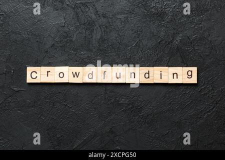 Parola CROWDFUNDING scritta su legno blocco. TESTO CROWDFUNDING sulla tabella del cemento per il vostro desing, concetto. Foto Stock