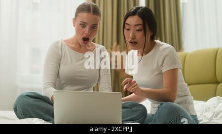 Felice sorridente ridendo eccitato multietnico multirazziale diversità due amici caucasico asiatico donne donne donne donne donne donne laptop online sconto gioire Foto Stock