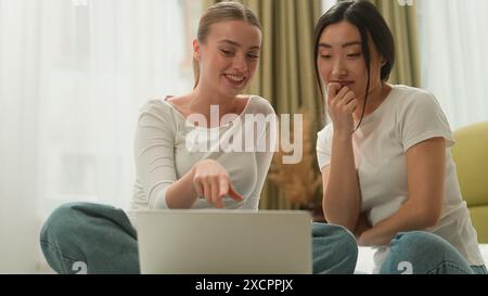 Due donne multirazziali felici multietniche donne persone diversità ragazze donna caucasica che parla con ragazza asiatica condividono notizie pettegolezzi sussurro sull'orecchio Foto Stock