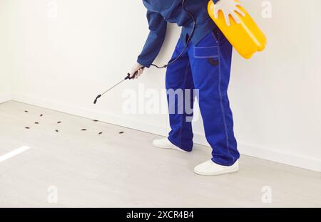 Disinfettante operaio spruzzando la casa con insetticida per eliminare gli scarafaggi Foto Stock