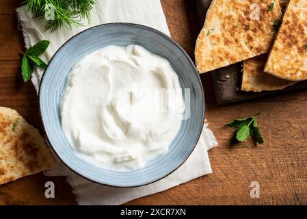 Salsa al formaggio Labneh con yogurt fatto in casa e Pita Pread per la tradizionale colazione mediorientale e mediterranea. Yogurt greco in ciotola blu, vista dall'alto. Foto Stock