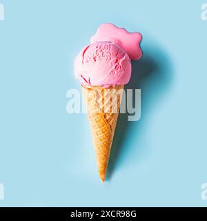 Gelato rosa che si scioglie e si riversa nel cono per waffle su sfondo blu pastello. Concept gastronomico estivo minimalista e creativo. Paletta di fragola fusa Foto Stock