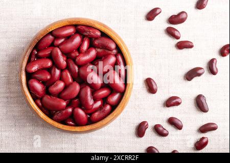 Fagioli in una ciotola di legno su tessuto di lino. Fagioli comuni cotti e in scatola, una varietà di fagioli comuni Phaseolus vulgaris. Foto Stock