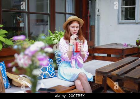 giovane donna che si diverte a bere limonata mentre riposa nel parco alla luce del sole. Atmosfera estiva Foto Stock