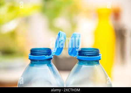 L'immagine cattura i tappi blu fissati su bottiglie di plastica trasparente, riflettendo gli sforzi per la sostenibilità ambientale previsti dalla direttiva UE Foto Stock