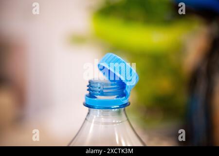 Un'immagine che cattura un tappo di plastica blu legato su una bottiglia trasparente, sottolineando le nuove normative UE in vigore dall'estate 2024 volte a ridurre l'inquinamento Foto Stock