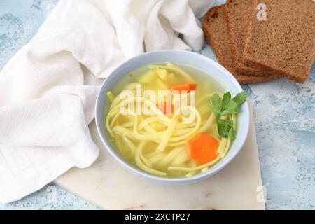 Ciotola di gustosa zuppa di pollo e pane su sfondo blu Foto Stock