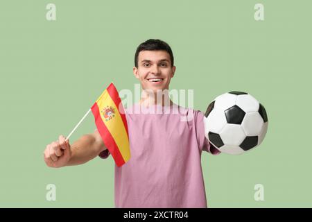 Giovane con palla da calcio e bandiera spagnola su sfondo verde Foto Stock