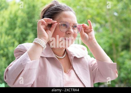 Donna d'affari matura guarda attraverso lenti correttive, lottando contro l'affaticamento visivo, l'usura della vista, gli occhiali correttivi stanchezza degli occhi Foto Stock