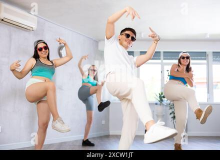 Adolescente che pratica movimenti di danza energici con un gruppo di adolescenti in classe di coreografia Foto Stock