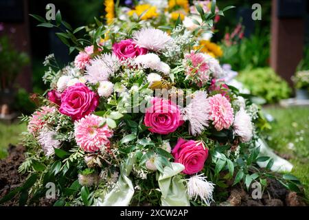 Fiori vivaci su una tomba fresca, che simboleggiano l'amore e il ricordo post-sepoltura Foto Stock