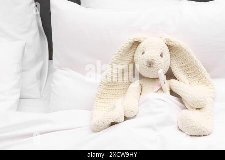 Giocattolo simpatico coniglietto con termometro sotto coperta nel letto Foto Stock